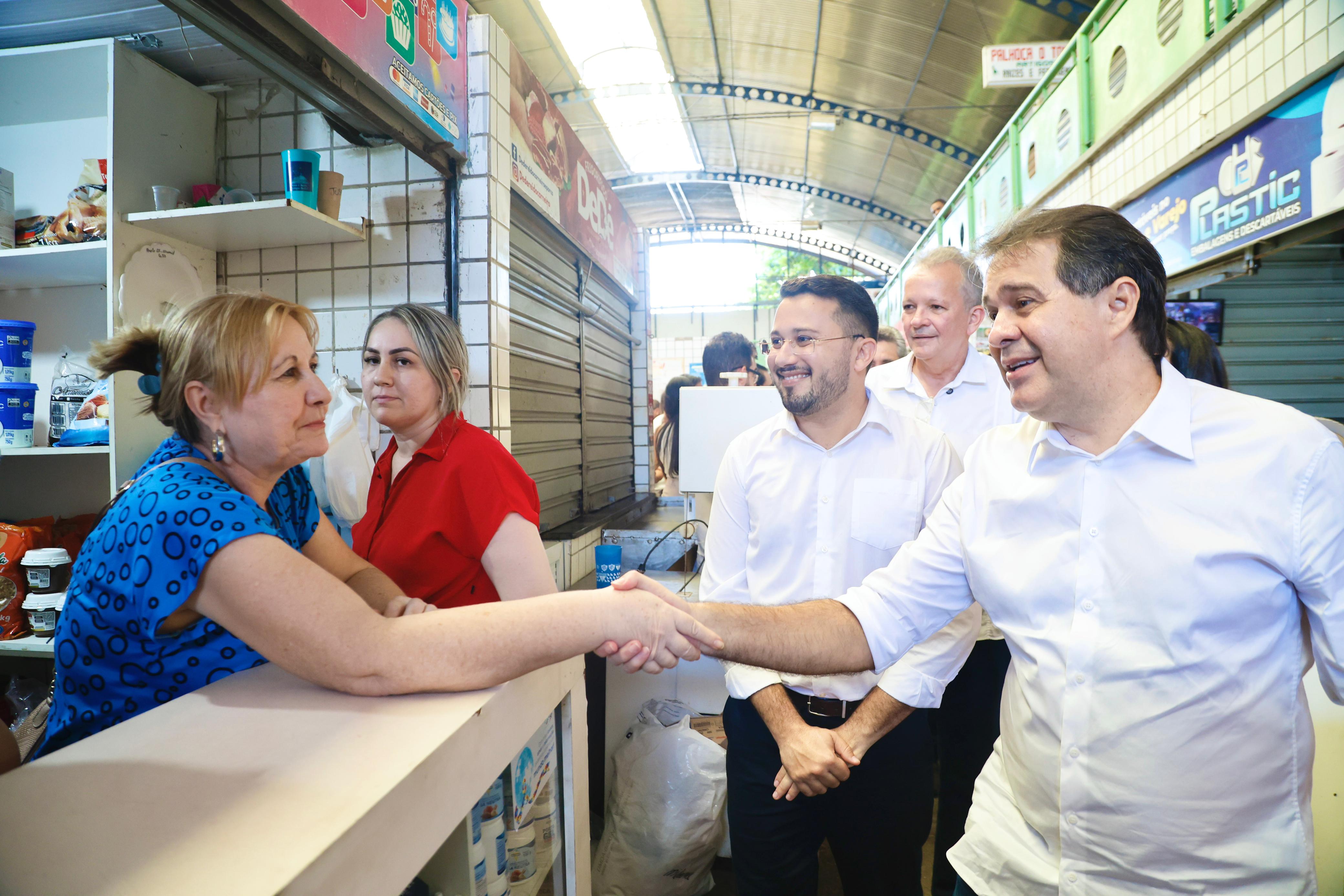prefeito cumprimenta uma feirante que está num balcão